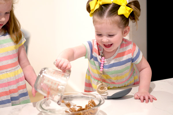 Preschooler adding peanuts into a bowl