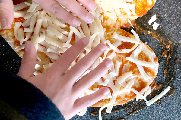 Kids spreading cheese on heart-shaped flour tortilla