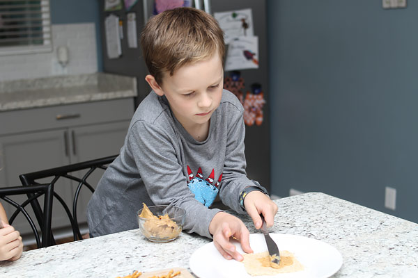 Young boy adding peanut butter to bread