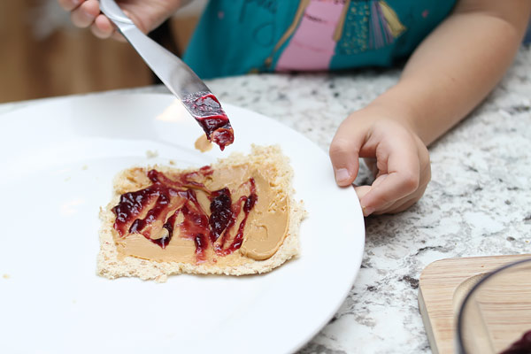 Young girl adding jelly to bread