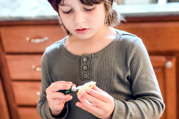 Child spreading cream cheese on crackers