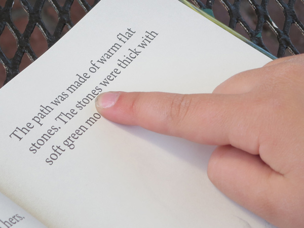Child pointing a word in a book