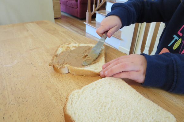 Preschooler spreading peanut butter on bread