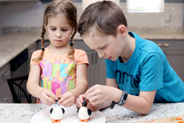 Children adding olive head and wings to hard-boiled egg
