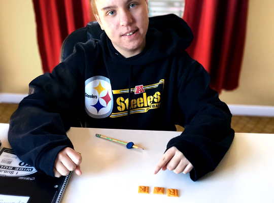 teen boy spelling words with letter crackers