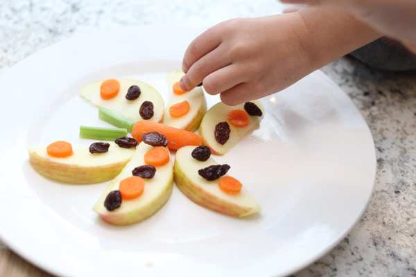Children adding raisins to snack
