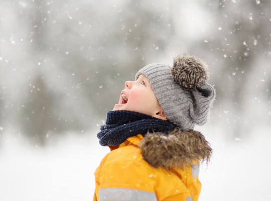 boy catching snowflakes on his tongue.