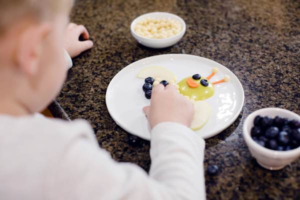 Child putting blueberries on plate