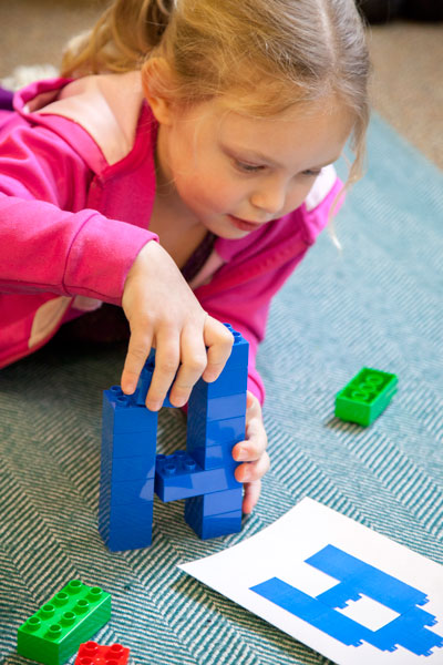 Preschooler building letter A with building blocks