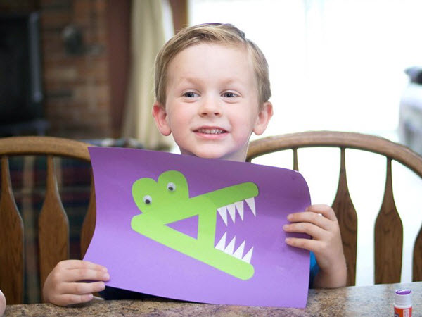 Little boy holding his finished letter A Alligator craft