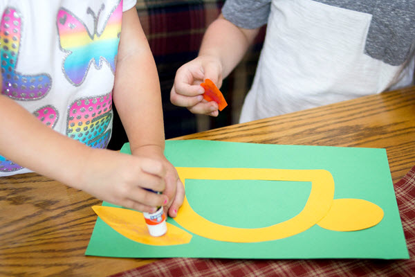 child gluing a wing onto letter d craft