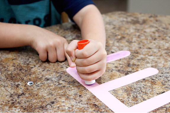 child applying glue to letter E