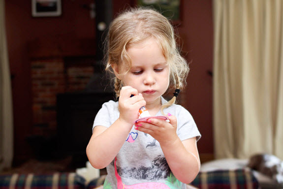little girl applying glue to craft