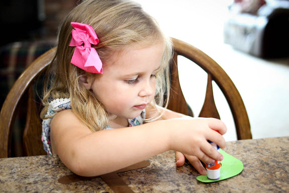 little girl putting glue on her letter i craft