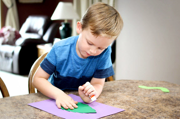 boy gluing a leave for his letter i craft