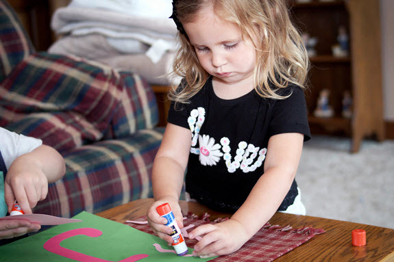 little girl gluing her letter j craft