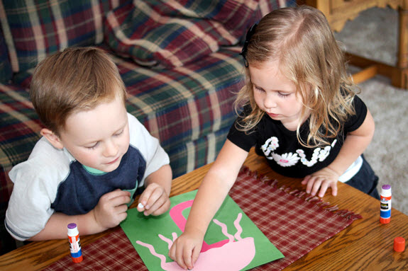 2 children adding googly eyes to their letter j craft
