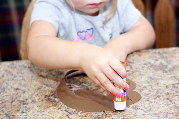 girl putting glue on her letter g craft