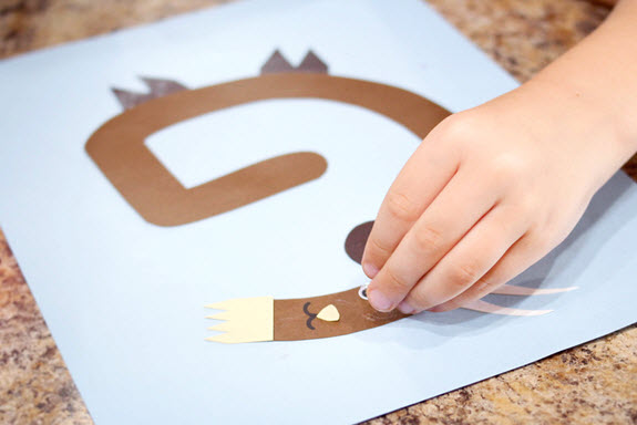 child affixing an eye to his letter G craft