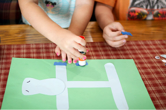 children gluing feet to their letter h craft
