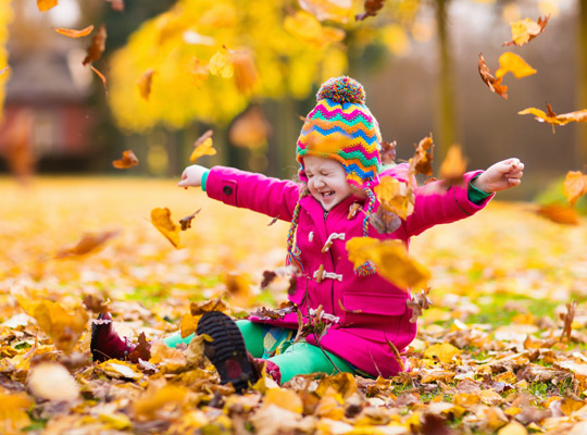 little girl playing in autumn leaves