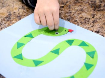 child gluing a googly eye onto his letter s craft