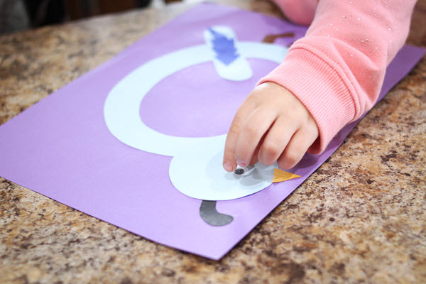 little girl gluing a googly eye on her letter q craft