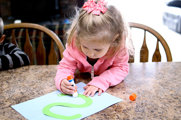 child gluing her letter s craft