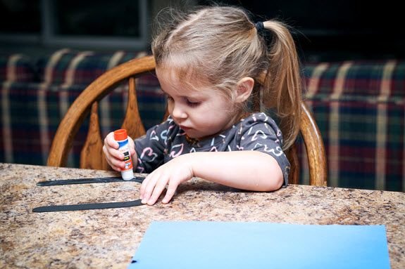 little girl gluing letter u craft