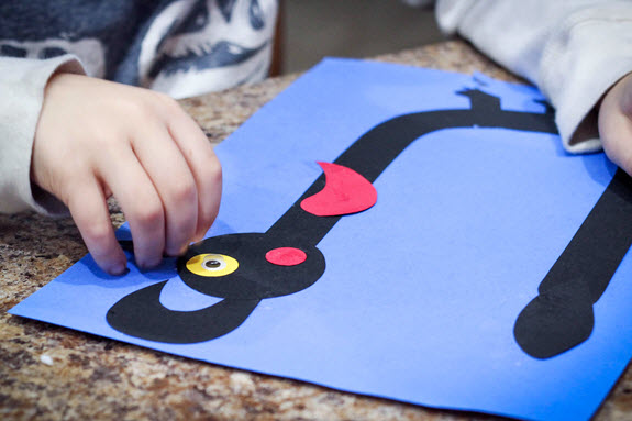 child gluing googly eye to letter u craft