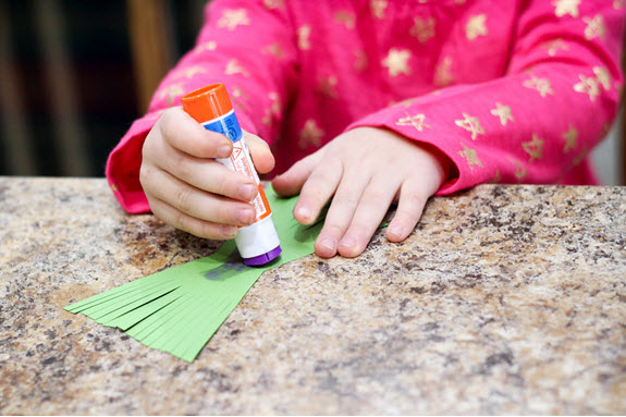 girl glues grass for her letter y craft