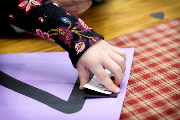girl glues a mane onto her letter z craft