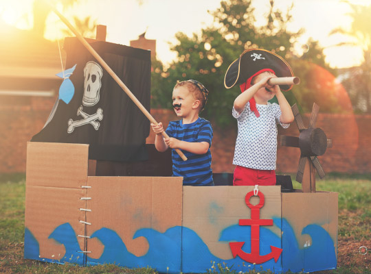 kids playing in a cardboard pirate ship