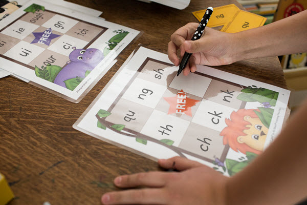 child writes phonograms on jungle bingo card