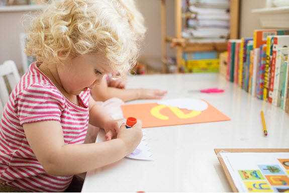 child glues a piece of lowercase e craft