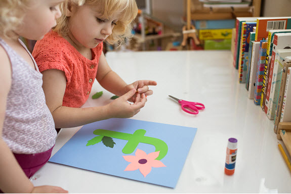 child glues flower to lowercase f craft