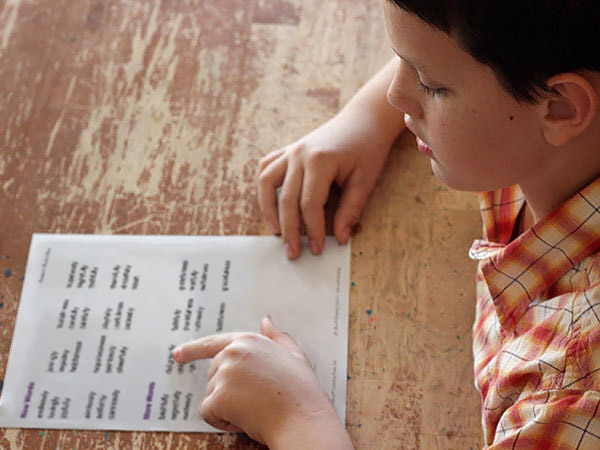 Young boy reading words off fluency sheet