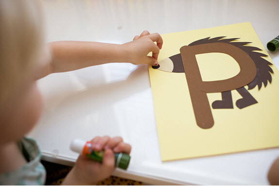 child puts a nose on her uppercase letter P craft