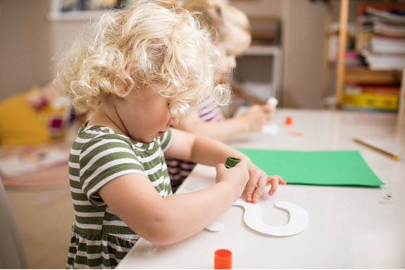 child puts glue on her lowercase s craft