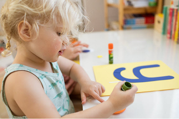child glues her lowercase y craft