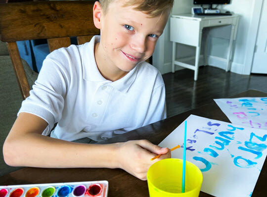 boy spelling words with water color paint