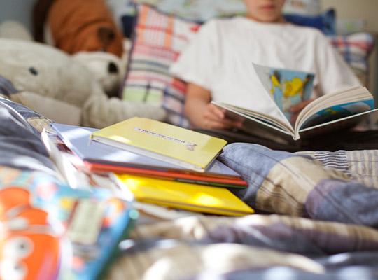 boy sitting in bed reading books
