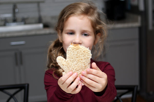 young girl holds bread mitten