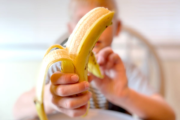 Preschooler peeling a banana