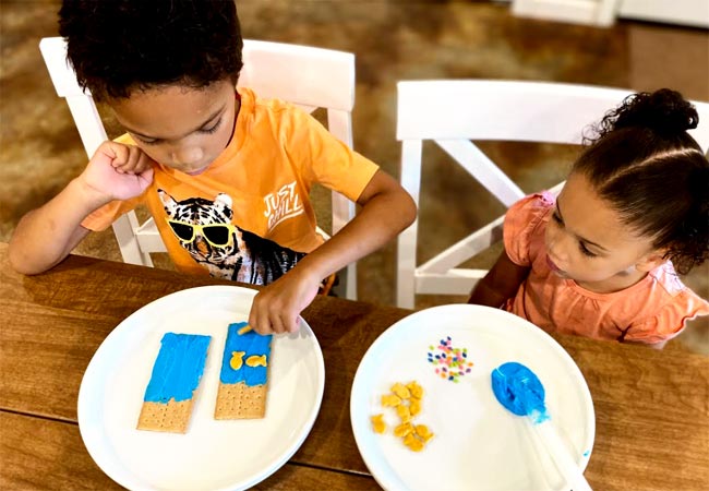 Children adding goldfish to graham cracker