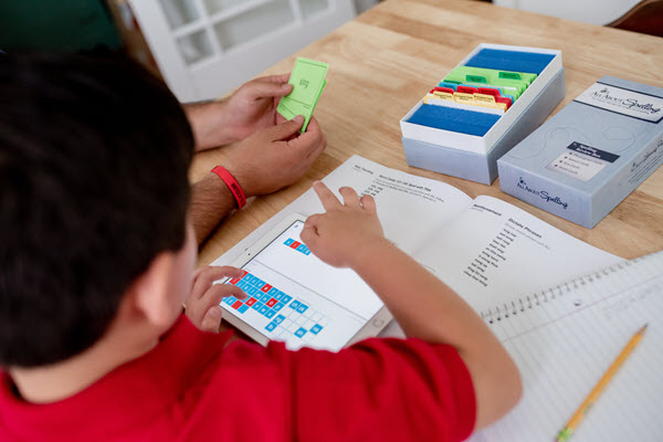 boy working on spelling with letter tiles