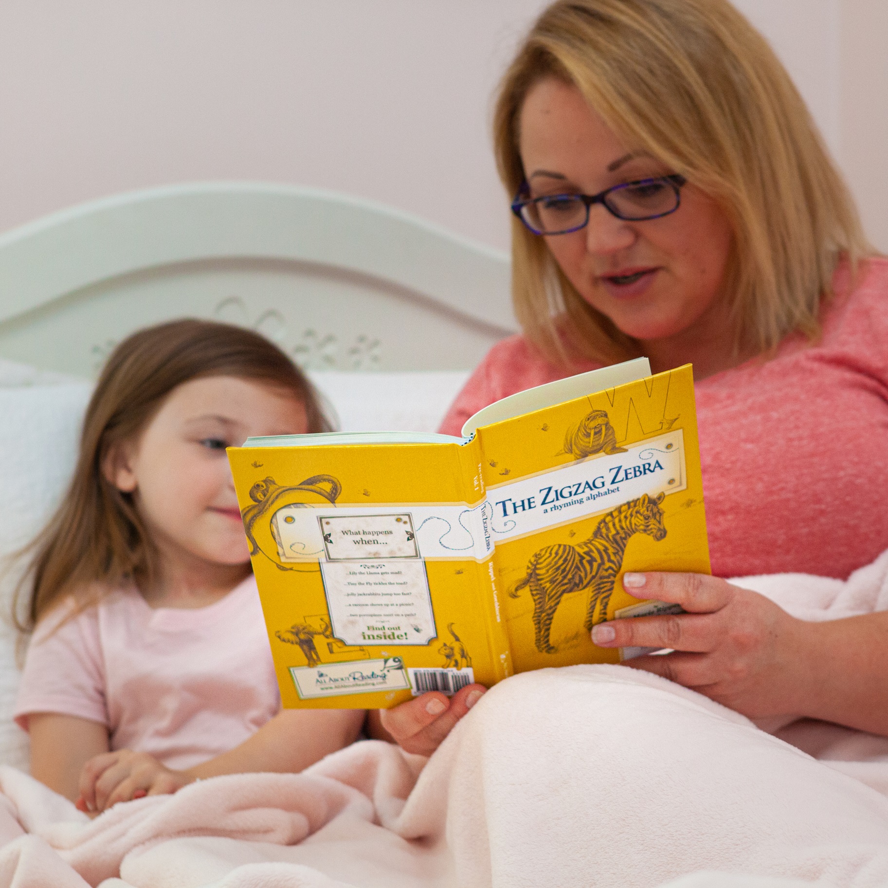 a girl and her mom reading together in bed
