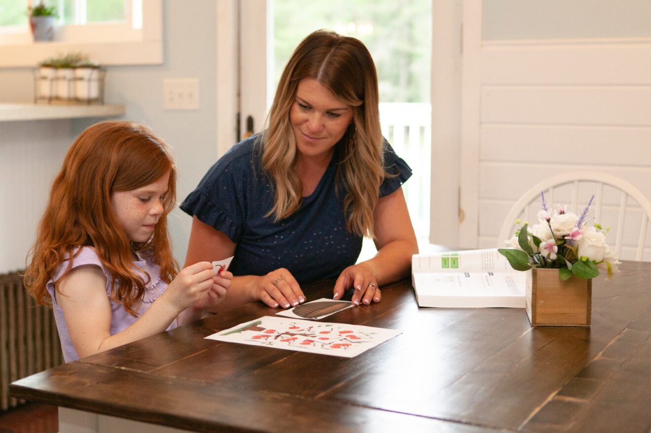 a mother and daughter practicing reading together using flash cards with pictures of cherries on the back