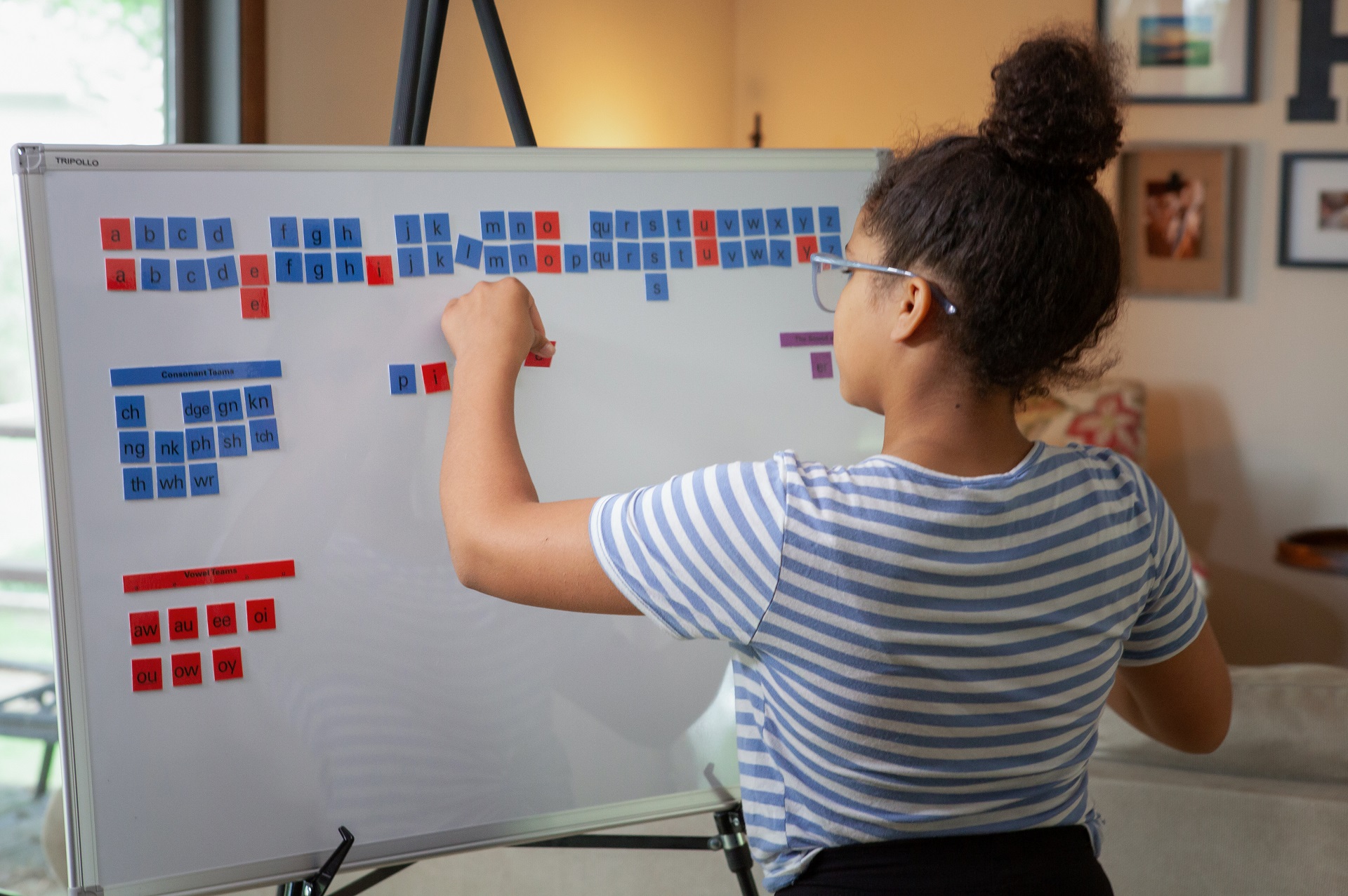 Student practicing spelling with letter tiles on a magnetic whiteboard