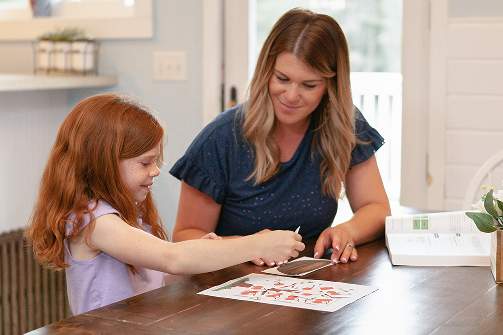 A woman teaching a girl to read by doing a fun activity at home